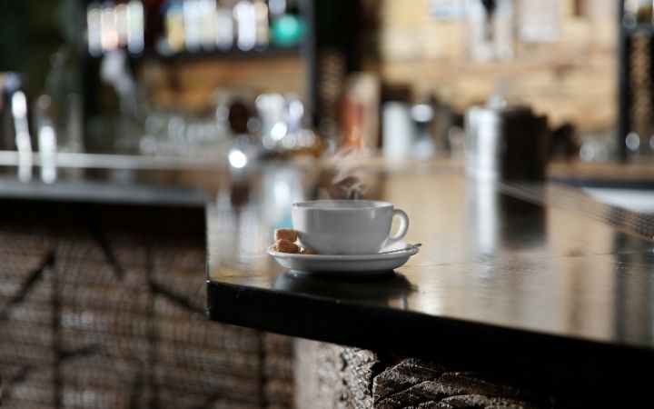 A cup of coffee on the edge of a coffee table